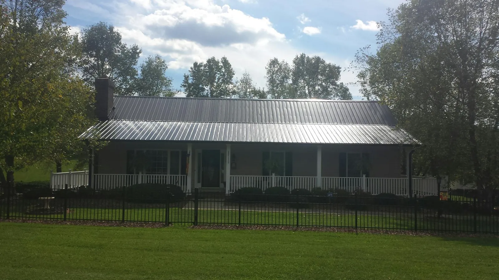 Gray metal roof on a brick ranch with a full width front porch — Gutter Guard Installation work by our crew in Elkins Park