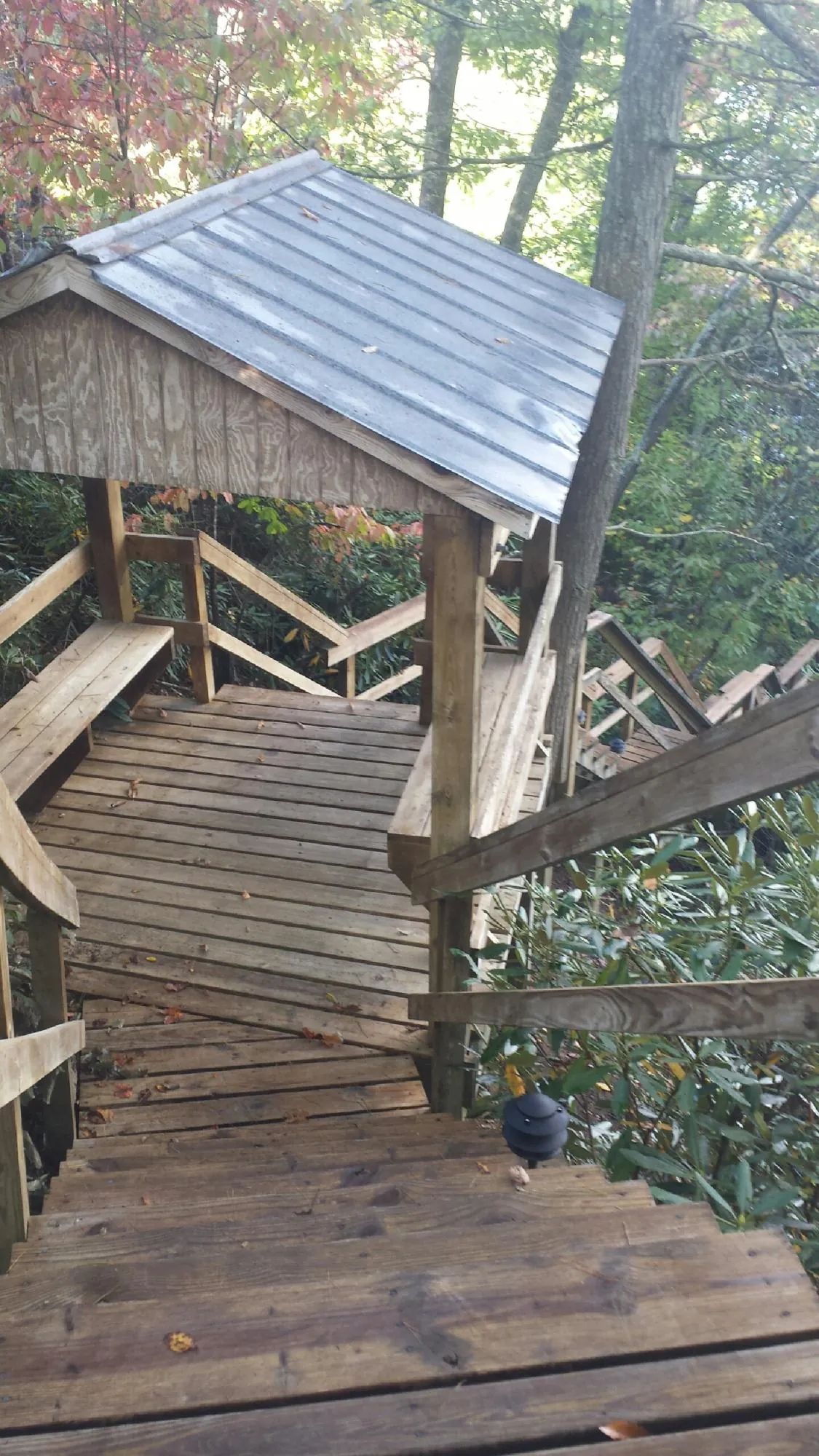 Metal roofed shelter over wooden steps on a wooded walkway — Skylight Repair & Installation work by our crew in Elkins Park